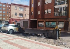 Los contenedores calcinados y un coche afectado por el fuego en Trobajo del Camino.
